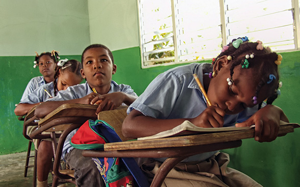 Trois filles et un garçon dans une salle de classe.