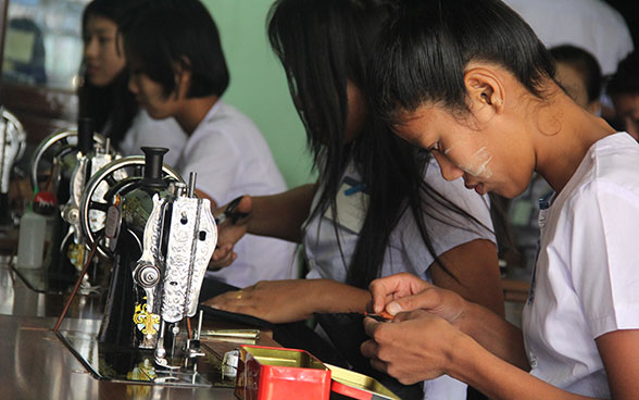 Junge Frauen in Myanmar arbeiten an Nähmaschinen.
