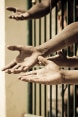 Mains tendues à travers les barreaux d’une cellule de prison.