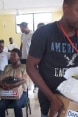 Haitianerinnen und Haitianer erhalten Schachteln mit Hygieneartikeln.