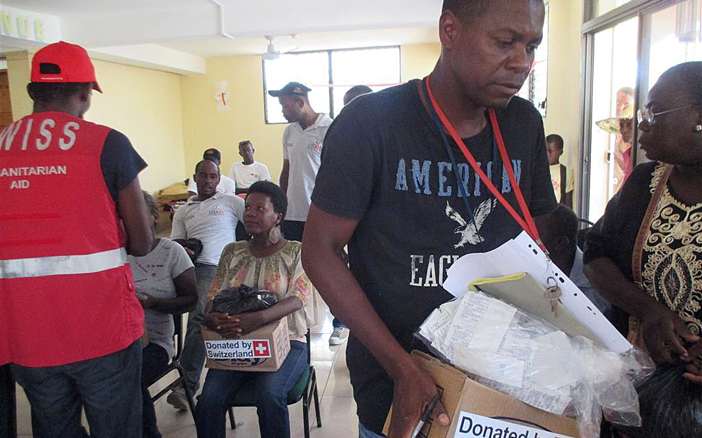 Des Haïtiens reçoivent des cartons contenant des articles hygiéniques. 