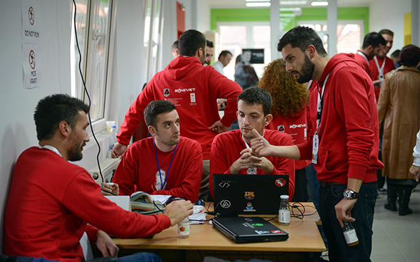 Four young developers sitting at a table discussing IT solutions designed to help the municipality create more transparency.