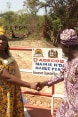 A woman and a man shake hands in front of a sign with Switzerland's logo and the names of the two towns involved in building the bridge.