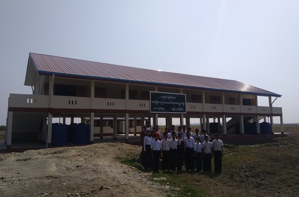 Une classe pose devant une école reconstruite.  