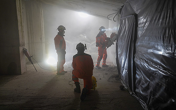 Trois spécialistes de la Chaîne suisse de sauvetage à l’intérieur d’un bâtiment détruit, durant un exercice de nuit.  