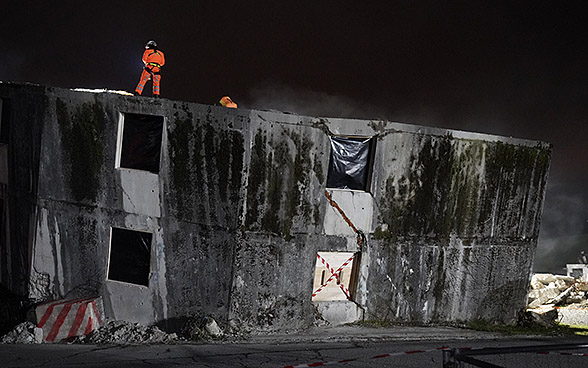 Des sauveteurs suisses sont postés sur un bâtiment détruit durant un exercice de nuit.  