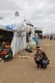 A female child with her dad beside a tent of the UNHCR with fruits and vegetables.