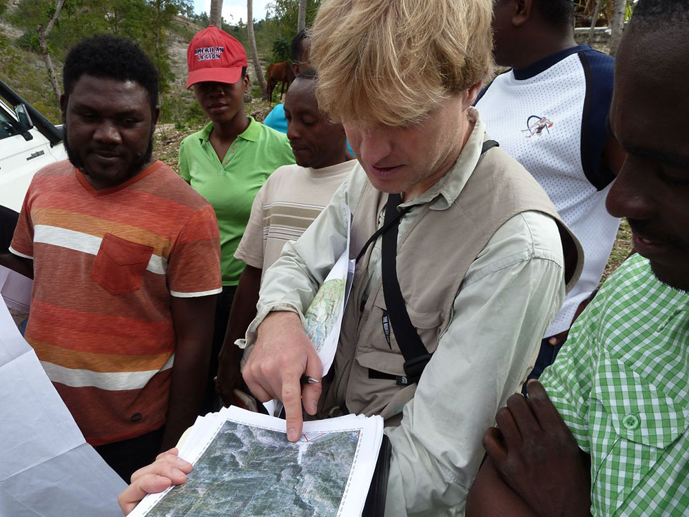 Ein Schweizer Experte, umgeben von Haitianischen Experten, zeigt auf eine Landkarte.