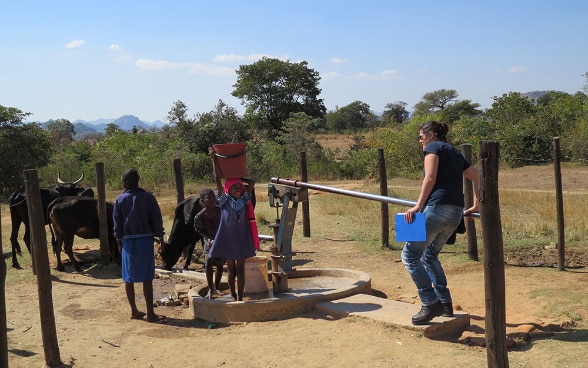 Une experte du CSA pompe l’eau d’un puit entouré d’enfants africains.