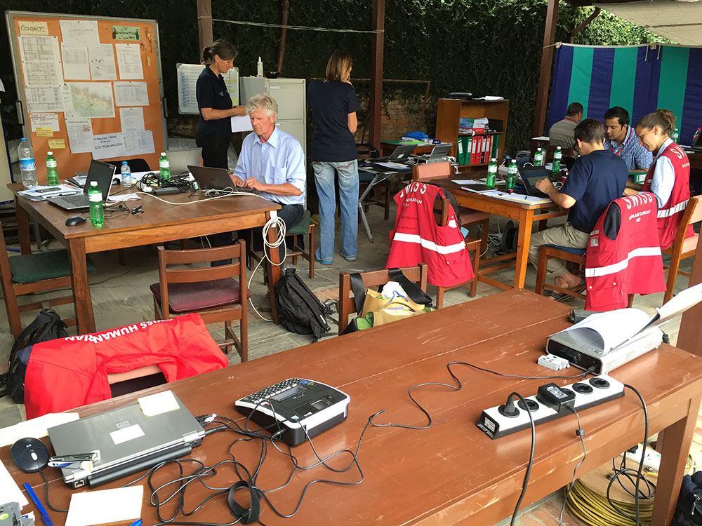 Mitarbeiter der Humanitären Hilfe bei der Arbeit in einem Büro, ausgestattet mit Mobiltelefonen und Computern.