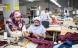 Tre persone formano altrettante cucitrici sul posto di lavoro in una fabbrica tessile.