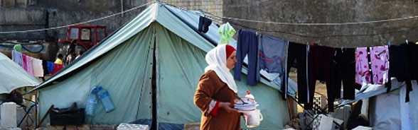 Une femme marche devant une tente de réfugiés