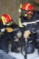 Two rescue workers training inside a destroyed building with a search device.