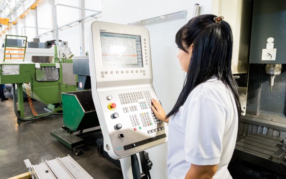 A young woman at a computer regulating machines.