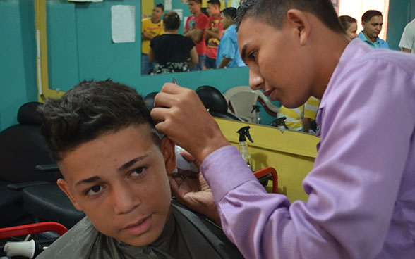 Ein angehender Coiffeur schneidet einem Jungen die Haare.