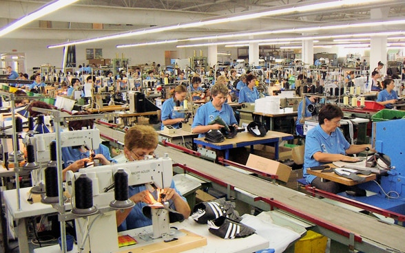 Vista in un edificio di fabbrica in Bosnia-Erzegovina, dove numerose donne cuciono scarpe su macchine da cucire