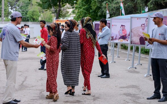 Des jeunes femmes reçoivent des tracts d’information dans une zone pédestre.