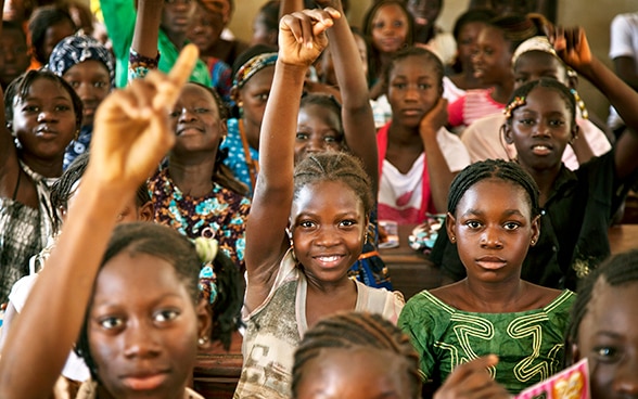 Varias jóvenes africanas levantan la mano durante una clase.