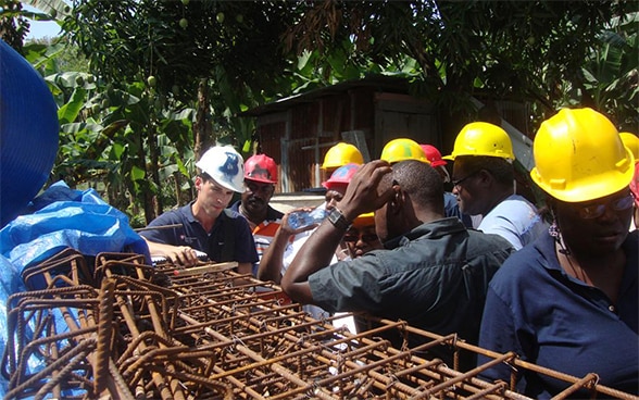 A member of the Swiss Humanitarian Aid Unit (SHA) talks to Haitian trainees.