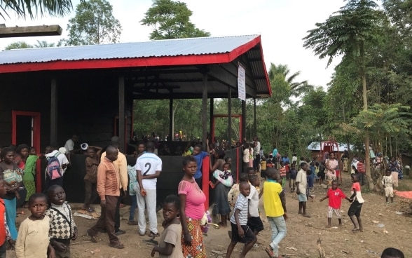 Dozens of children, mothers and other adults mill about inside and outside the 'Espace amis des enfants'. 