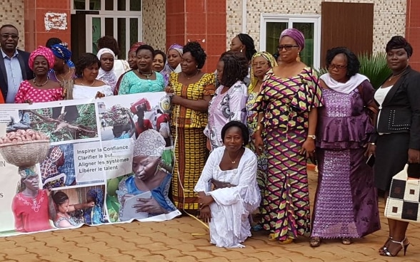 A group of women members of communal and municipal councils pose for a group photo holding a banner.