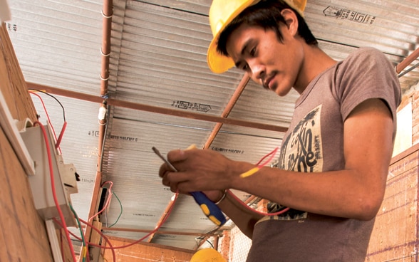 Tre giovani apprendisti seguono una formazione per diventare elettricisti in Nepal.