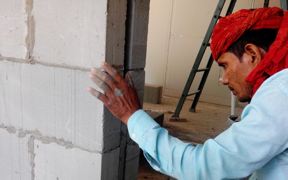 Un maçon travaille à la réalisation d’un mur en ciment.