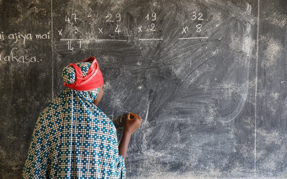 Descrizione: Una giovane scrive con il gesso su una lavagna in una scuola in Niger.