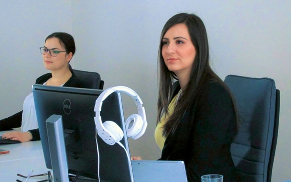 Two young women work on computers. 