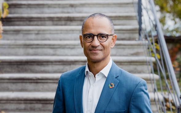 Foto de Christian Frutiger, con traje de chaqueta azul claro y camisa blanca.