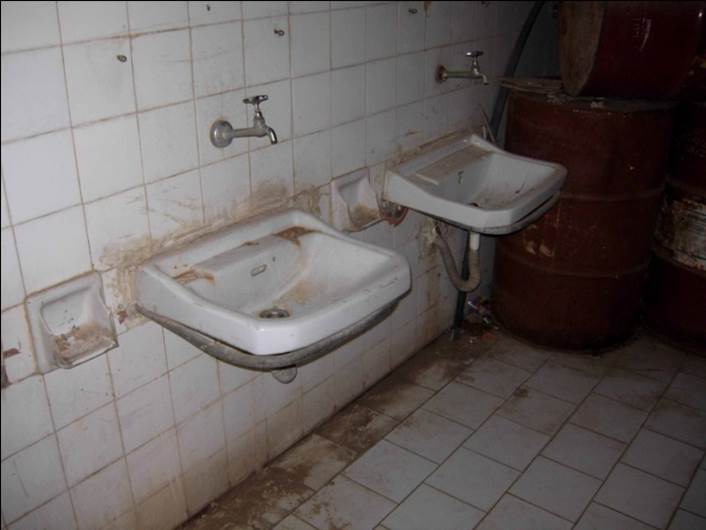 Deux robinets sales avec des carrelages endommagés sur les murs.