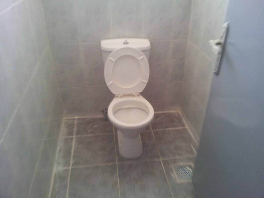 Photo of a new toilet in a freshly-tiled cubicle.