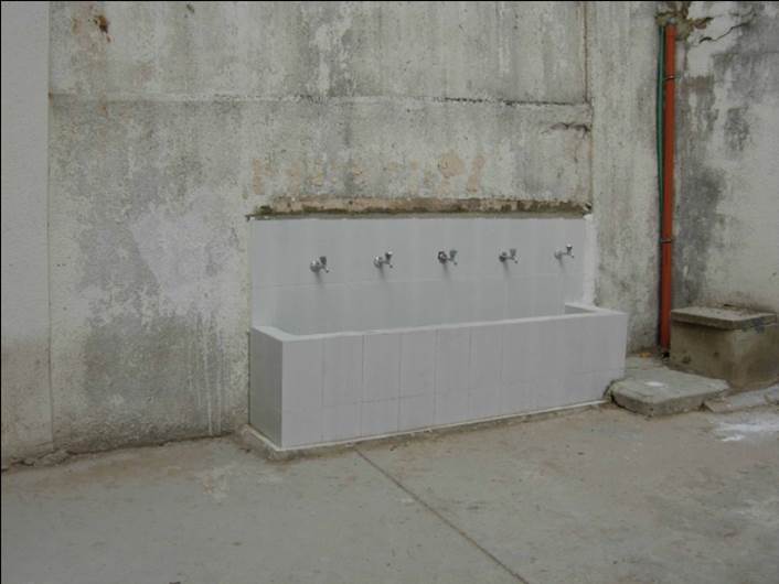 Un lavandino comune completamente rifatto con cinque rubinetti.