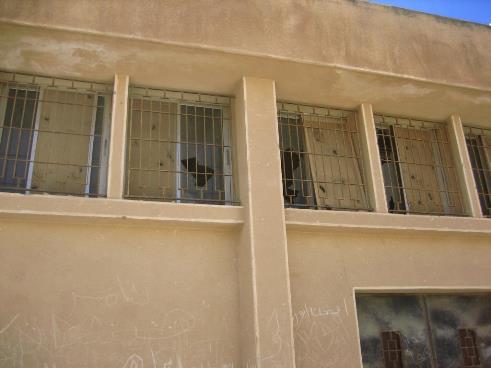 Façade d'une école endommagée, avec des vitres brisées. 