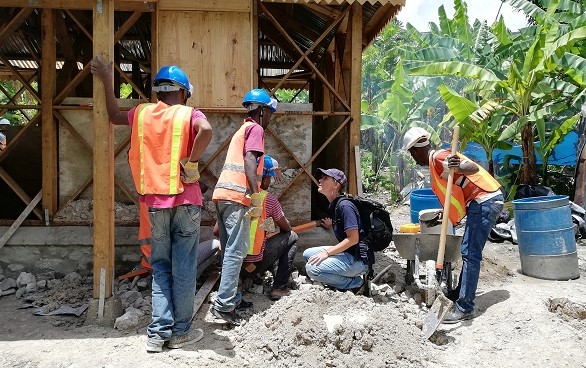 Une spécialiste du Corps suisse d'aide humanitaire devant un chantier avec des spécialistes haitiens. 