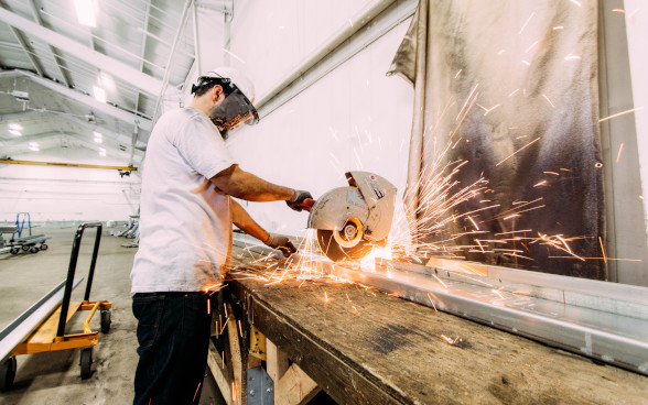 A man cuts metal with a circular saw.