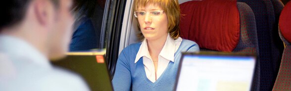Un uomo e una donna lavorano al computer in treno
