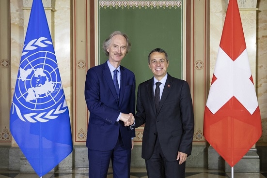 Le conseiller fédéral Cassis et Geir Pedersen se serrent la main à Berne. A l'arrière-plan, vous pouvez voir les drapeaux de la Suisse et de l'ONU. 