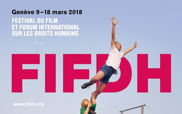 A woman holding onto a man's leg, keeping him from flying away. The FIFDH logo is in the background.
