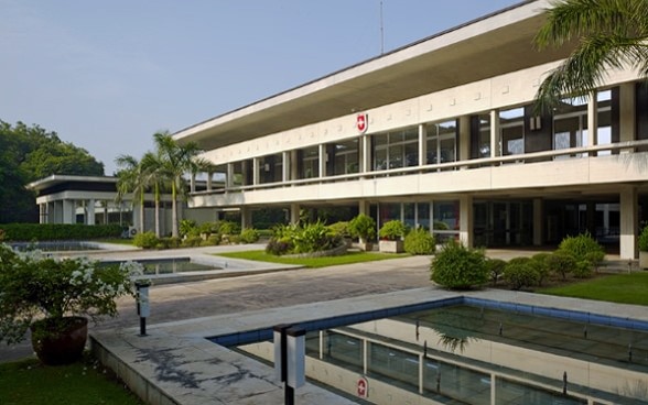 Zweistöckiges Gebäude der Botschaftskanzlei mit Wasserbecken im Vordergrund.