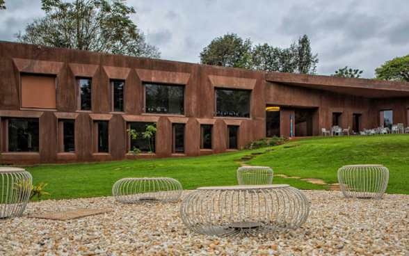 Le bâtiment ocre rouge de l’Ambassade de Suisse à Nairobi, avec des sièges de jardin au premier plan.