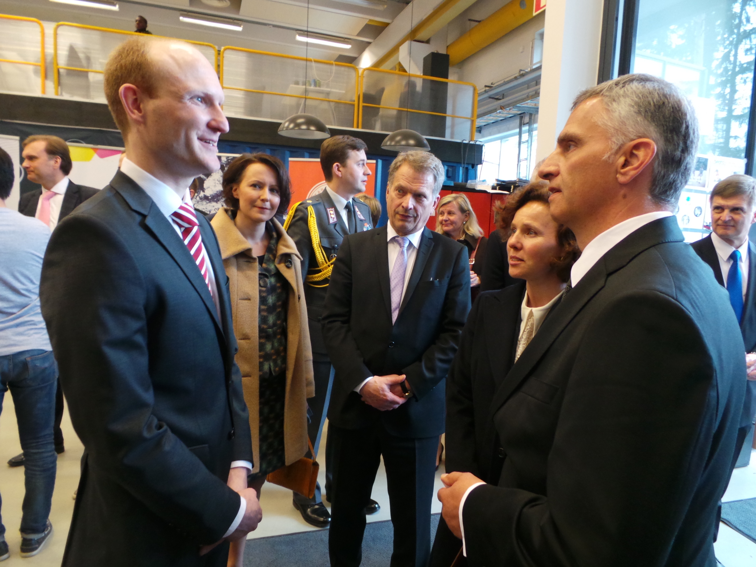 Didier Burkhalter und Sauli Niinistö mit ihren Ehefrauen an der Universität in Helsinki. Sie unterhalten sich mit einem Schweizer Forschenden.