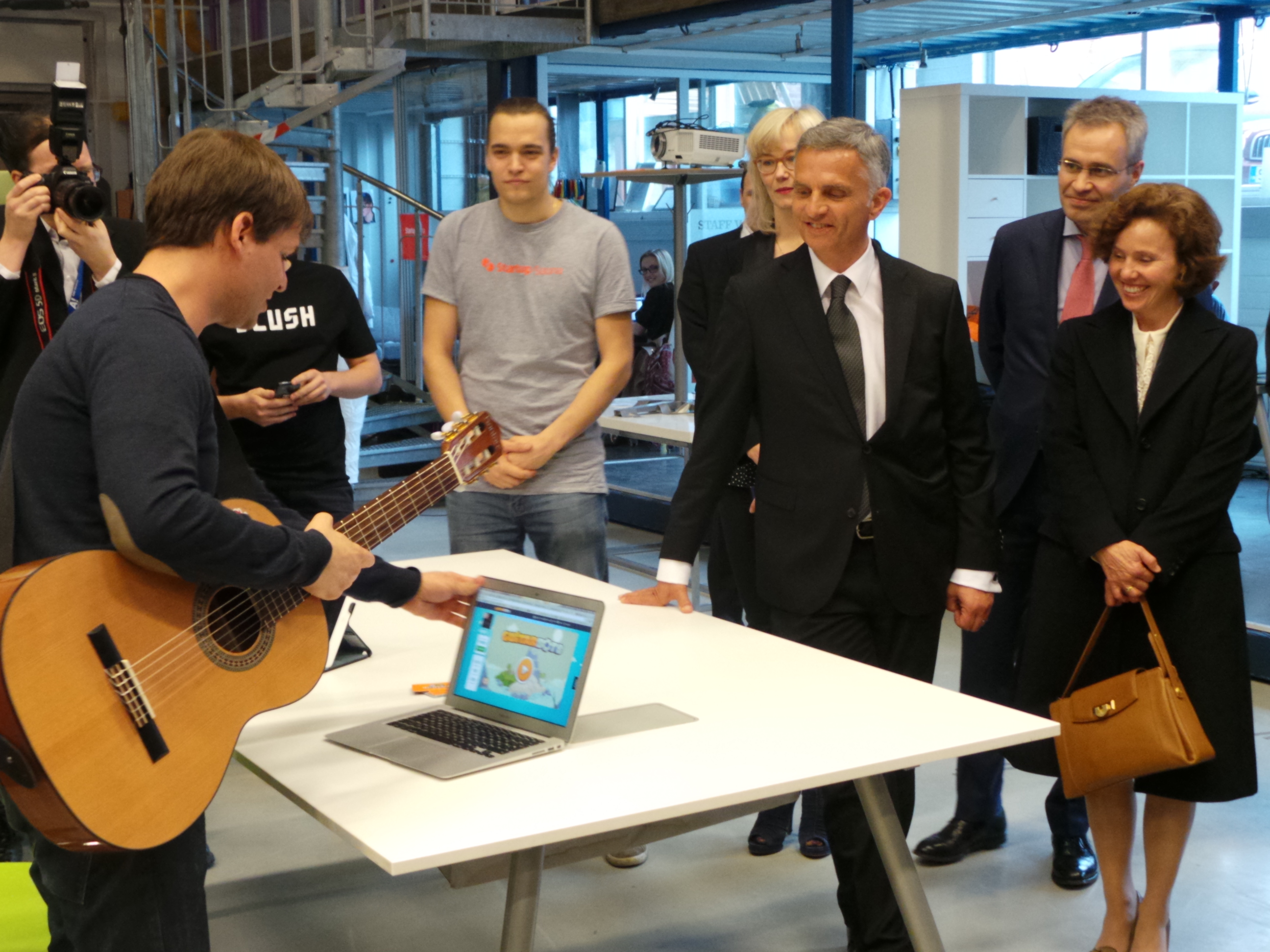 Un Suisse explique un programme informatique pour apprendre à jouer de la guitare au président de la Confédération Burkhalter et à son épouse.