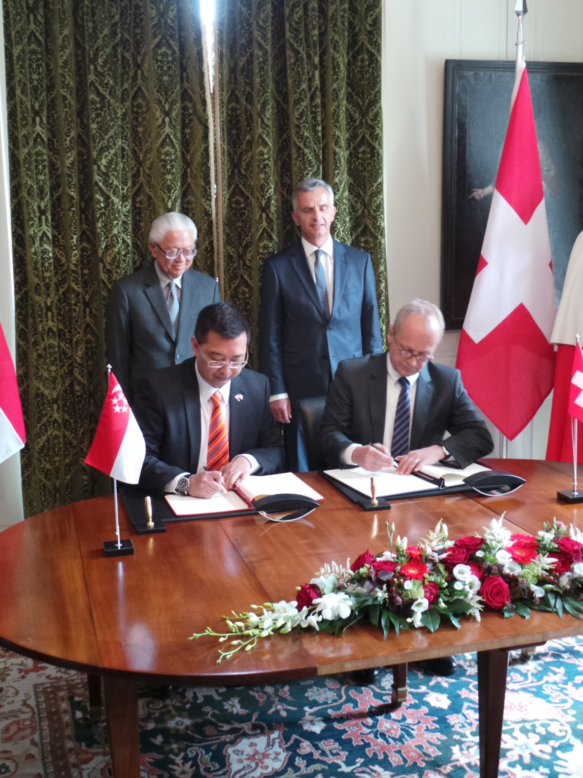 The deputy state secretary, Beat Nobs, and Simon Wong sign the declaration on deepening the partnership, while the President of the Swiss Confederation, Didier Burkhalter, and the President of the Republic of Singapore, Tony TAN Keng Yam, look on.