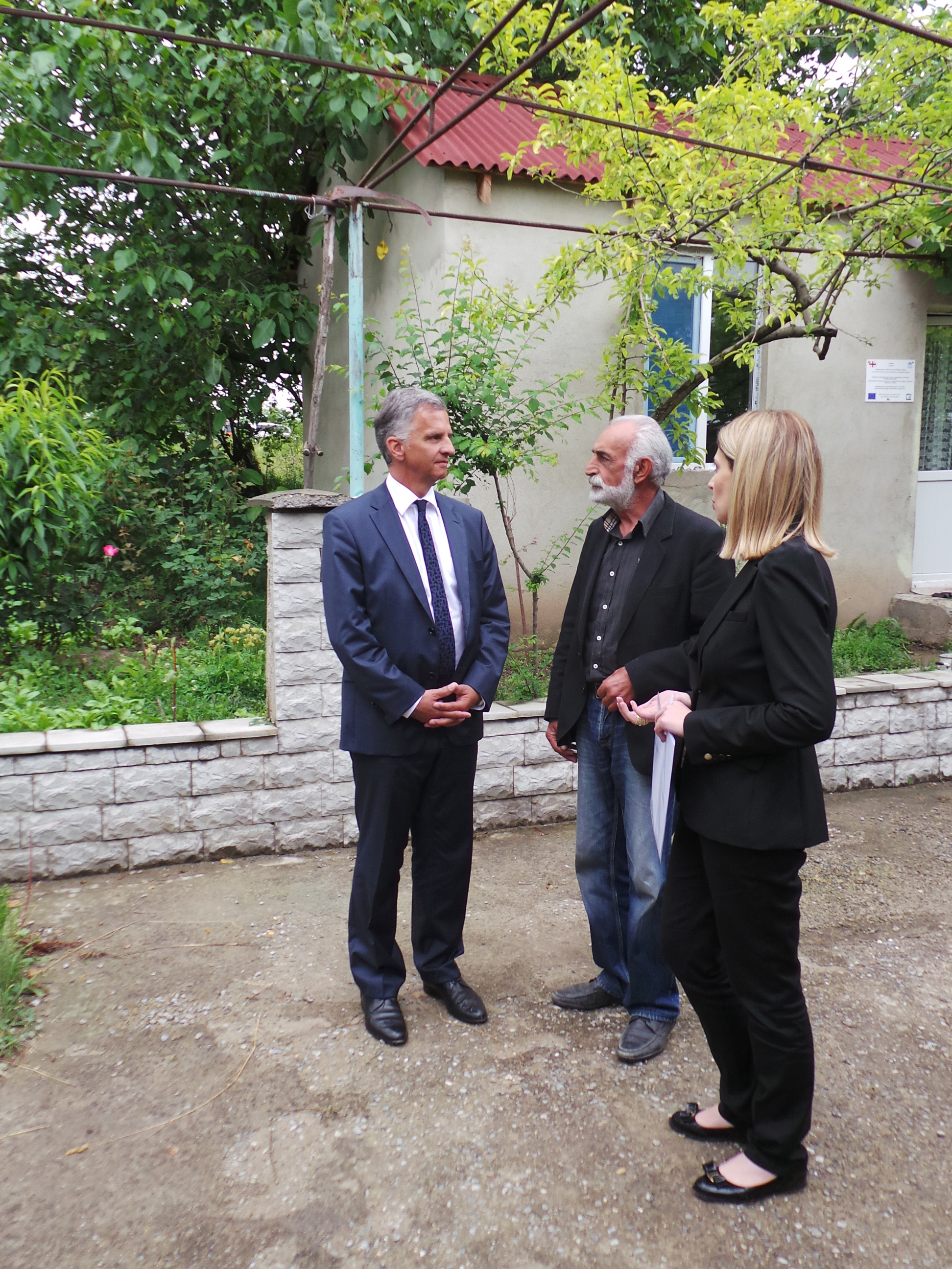 Bundespräsident Didier Burkhalter spricht mit dem Eigentümer eines ehemals kriegszerstörten Hauses, das mit Unterstützung der DEZA repariert worden ist.