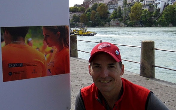 Il curatore Ashley Woods davanti al primo pannello della mostra fotografica «Making Peace» sulle rive del Reno a Basilea