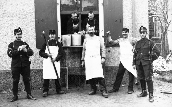 Photographie noir et blanc d'un groupe de soldats et de cuisiniers de l'Armée suisse durant la Première Guerre mondiale. © Keystone