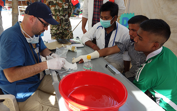 Un membro dell'équipe medica svizzera fascia la mano di una persona lesionatasi a causa del terremoto in Nepal.