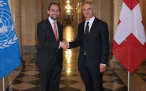 Il consigliere federale Didier Burkhalter con l’Alto commissario dell’ONU per i diritti umani Zeid Ra’ad Al-Hussein a Palazzo federale, a Berna, di fianco alla bandiera svizzera e a quella dell’ONU.