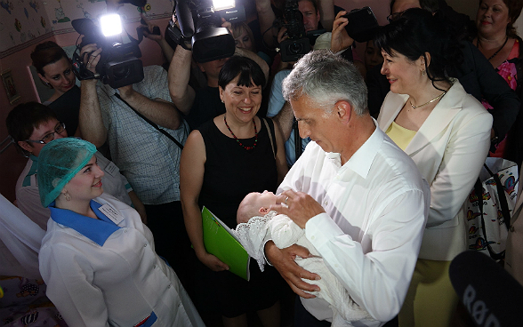 Didier Burkhalter hält einen Säugling im Arm.
